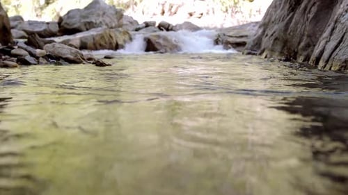slow motion shot of fast water moving down the rock fall into the pool of water beneath