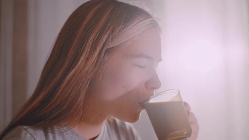 Close Up Woman Sipping Tea Indoors Under Soft Sunlight