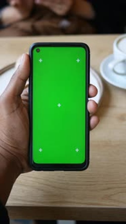 Hand Holding Smartphone with Blank Green Screen Display