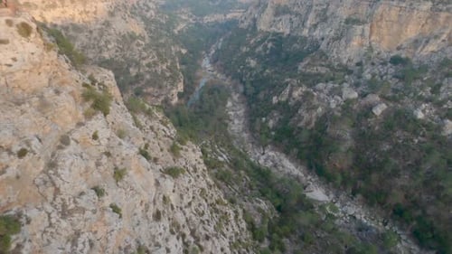 Drone vole dans le canyon avec un ruisseau au fond des forêts et des rochers