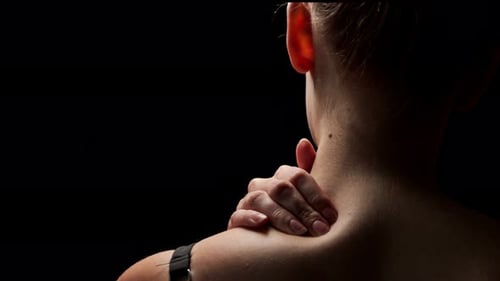 Shot from behind, close-up on the neck of a woman feeling pain in her muscle in shoulder and massagi