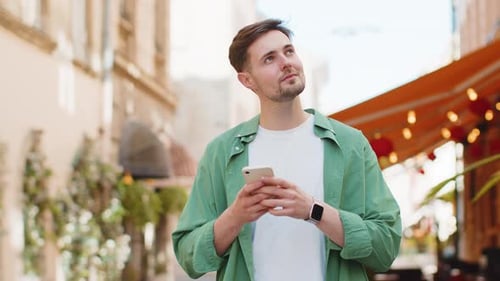 Young Man Using Phone on City Street