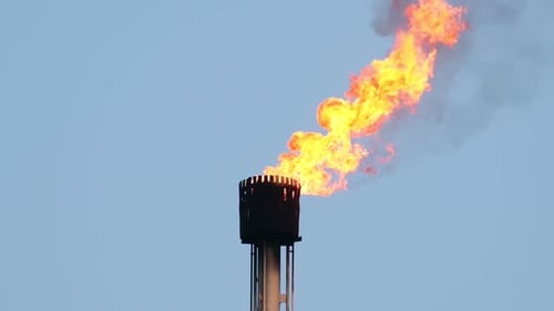 Torch of Gas burning fire flames from chimney pipe. Sky background. Environmental