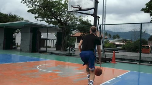 view from the back of a man with a ball running to the basketball hoop