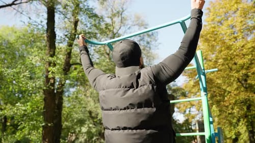 A Man Pulls Himself Up on a Horizontal Bar