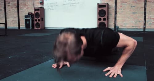 Young caucasian man in sportswear does pushups on the floor of a gym during workout