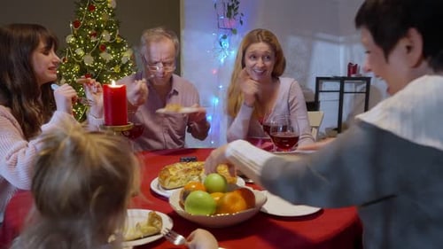 Family shares meal around Christmas tree at home