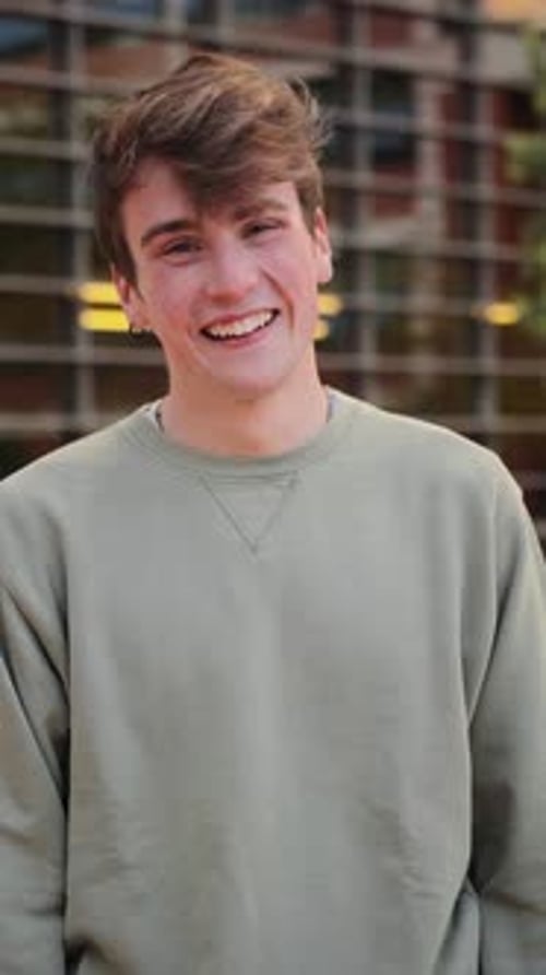 Smiling Young Adult Standing Outdoors in Front of Building