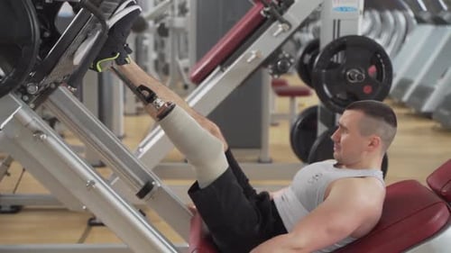 Determined Man Doing Leg Press with Prosthetic in Gym