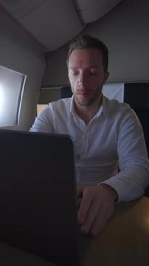 Man Opens Laptop in Airplane Cabin and Types