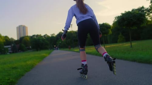 Back view of unrecognizable young woman rollerblading in the park