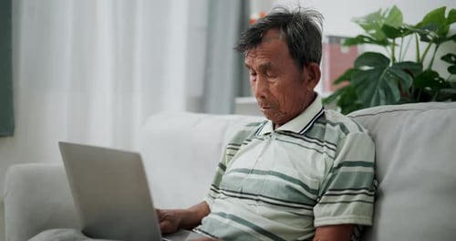 Senior man using laptop while sitting on sofa