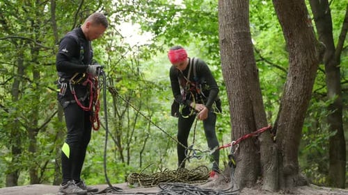 Dois alpinistas, menino e menina, com seus equipamentos em uma floresta rochosa de montanha. Cordas de segurança de dois lances de
