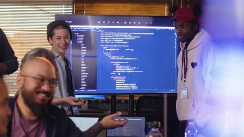 Smiling hackers at a hackathon discussing computer code on screen together