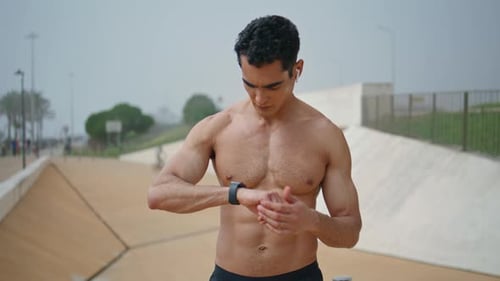 Muscular Man Checks Smart Watch Then Begins Running