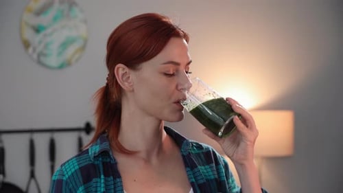 Young Woman Drinks Green Smoothie Indoors