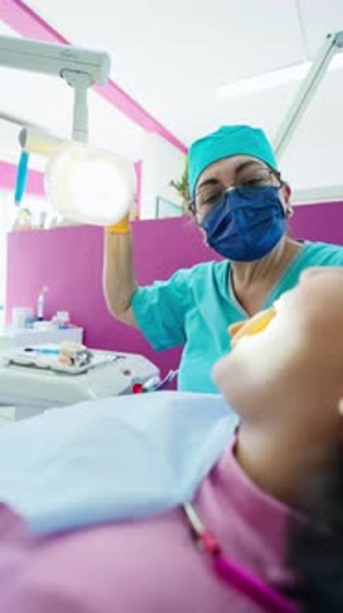 Dentista sénior que usa una lámpara dental sobre un paciente en la clínica
