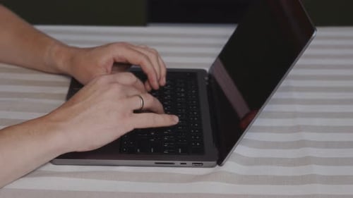 Wide Close Up of Male Hands Typing on Laptop Keyboard at Table