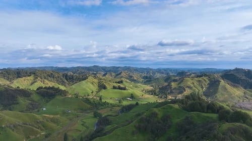 Aerial flies over classic New Zealand inland hill country towards remote holiday cottages.