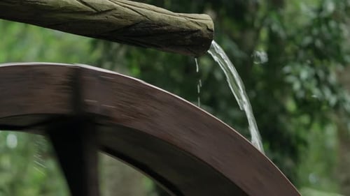 Nahaufnahme von Wasser, das auf ein hölzernes Wasserrad fällt