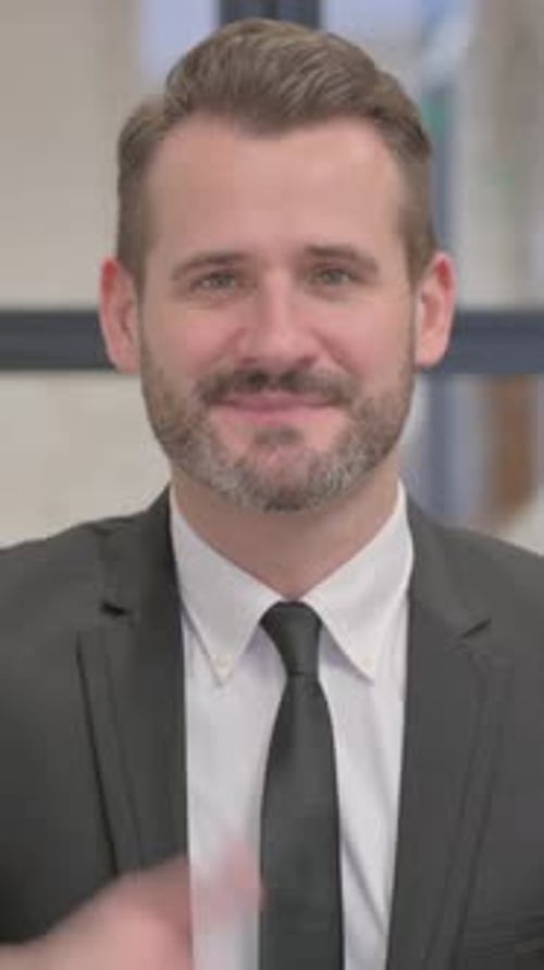 Smiling Man in Suit Gives Thumbs Up