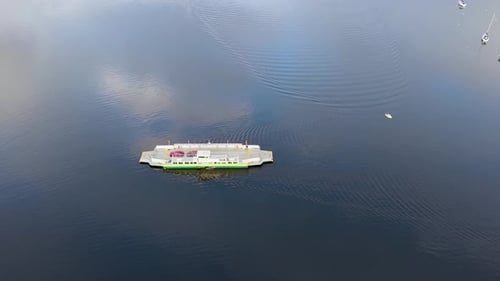 Seitliche Drohnenaufnahme der Fähre über den Lake Windermere mit roten Autos und ruhigem Wasser