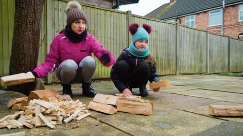 Woman and Girl Sorting Wood in Backyard