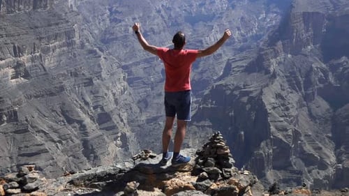 Junger Mann erreicht siegreich den Gipfel des Canyons in Superzeitlupe