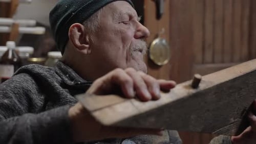 Elderly Male Master Works in His Workshop Restoring Furniture