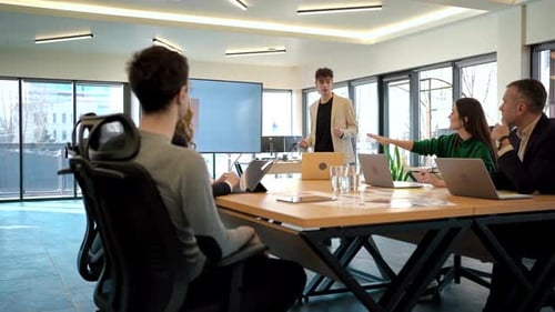 Young worker leading business meeting in an office, discussing business affairs with other workers u