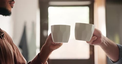 Two People Toasting with Mugs in Bright Kitchen