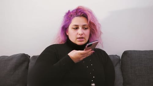 Eine Frau mit rosafarbenen Haaren benutzt den KI-Gesangsassistenten per Smartphone.