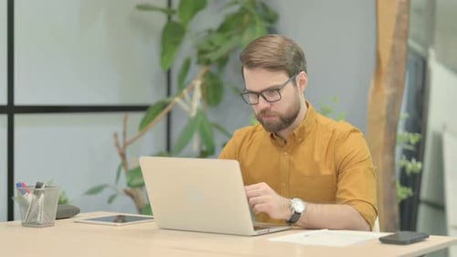Young Man Reacting to Loss While Working in Office