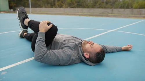 Man Trains By Stretching In Blue Field Outdoors