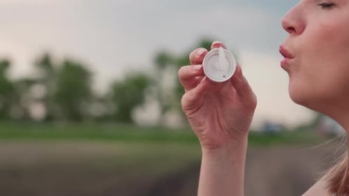 Gros plan soufflant des bulles avec une baguette sur fond de terres agricoles flou