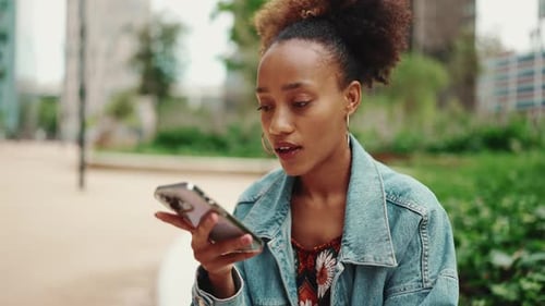 Close-up of girl leaving voice message on mobile phone against modern city background