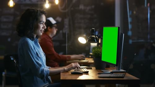 Beautiful Female Office Employee at Her Desktop Works on a Mock-up Green Screen Personal Computer.