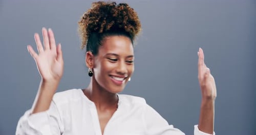 Woman Smiling and Dancing in Front of Grey Background