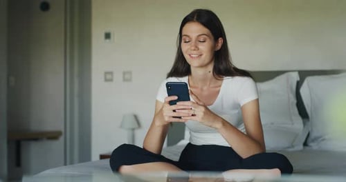 Woman Smiling Using Mobile Phone on Bed