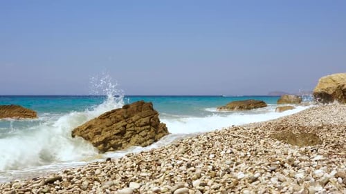 Sea waves splashing on rocky shore with blue turquoise sea background in Ionian coastline