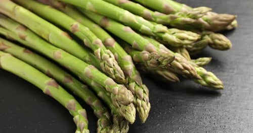 Wasser auf frischen rohen Spargel auf schwarzem Tisch sprühen, Nahaufnahme