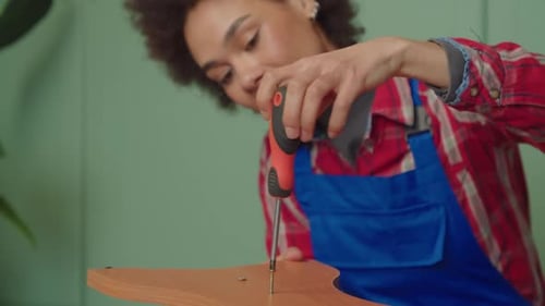 Close Up of Black Handywoman Repairing Furniture with Screwdriver Indoors