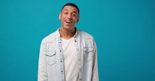 Joven afroamericano agita la palma de la mano en un gesto de saludo, da la bienvenida a alguien y expresa lo positivo