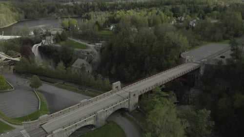 Drone shot, flying over a bridge and revealing a big waterfall in a canyon.