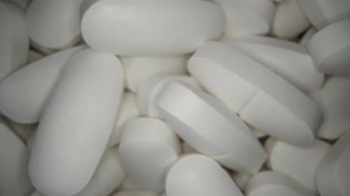 A black jar with white tablets rotates on a black background. Dolly slider extreme close-up. Top vie