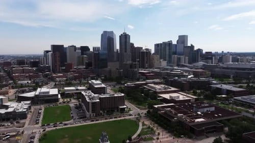 Drone approaches dense downtown Denver with roads and modern highrise buildings