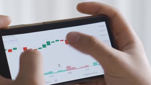 Homme vérifiant le graphique des cryptomonnaies et des cours des actions sur le marché boursier numérique sur l'écran du téléphone.