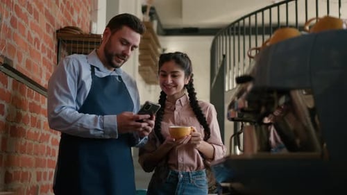 Caucasian Man Waiter Bartender Speaking to Arabian Woman Restaurant Manager Behind Counter Talk on