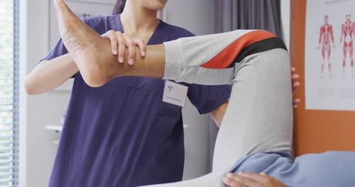 Diverse female physiotherapist and senior male patient in hospital physical therapy session on leg
