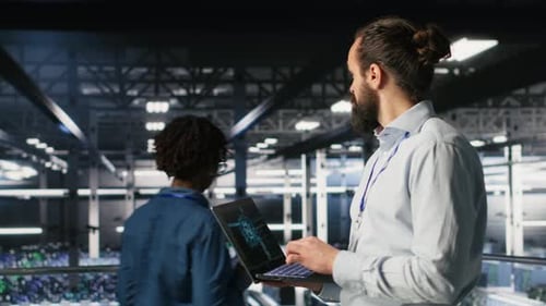 Technician Holding Laptop Walking on Server Farm Platform